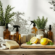 Natural eco-friendly cleaning ingredients displayed on a wooden countertop, featuring amber glass spray bottles, jars of cleaning powders, fresh lemons, a natural sponge, herbs in terracotta pots, and reusable cleaning essentials in soft sunlight.